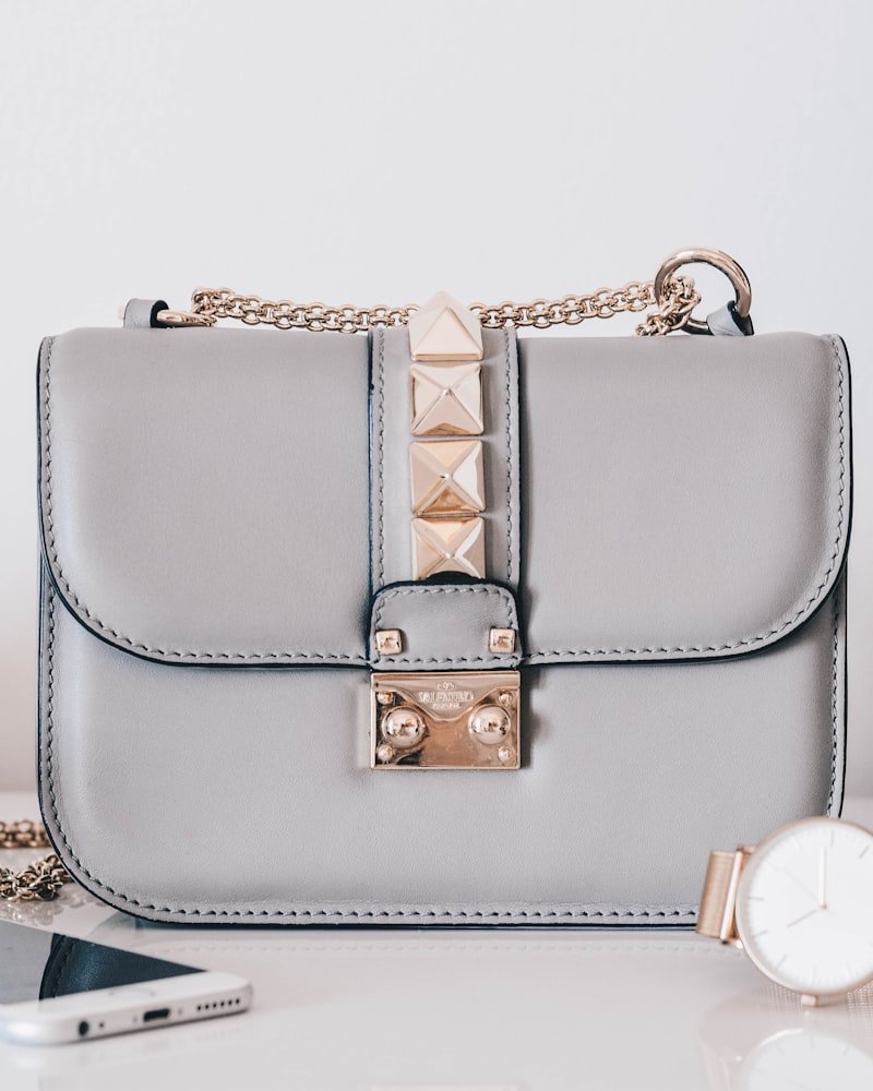 Dove grey shoulder bag with gold chain strap and studded flap