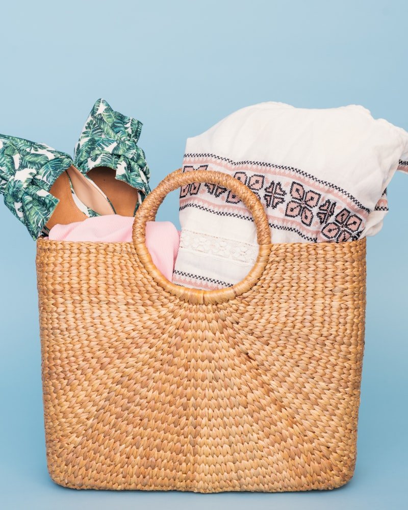 Round-handled woven straw tote bag holding folded printed fabric