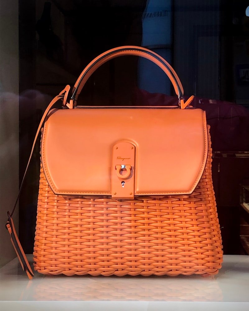 Tan leather handbag with a woven wicker body and flap closure